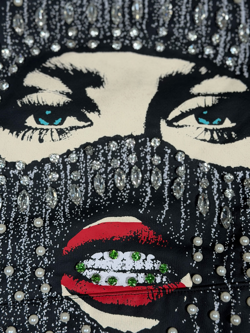 Dopetivity black hoodie featuring a graphic face mask print embellished with shimmering rhinestones and pearls.