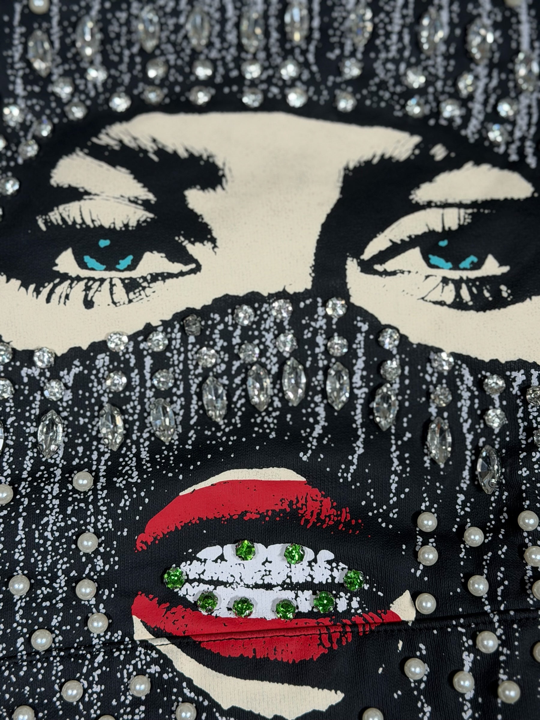 Dopetivity black hoodie featuring a graphic face mask print embellished with shimmering rhinestones and pearls.